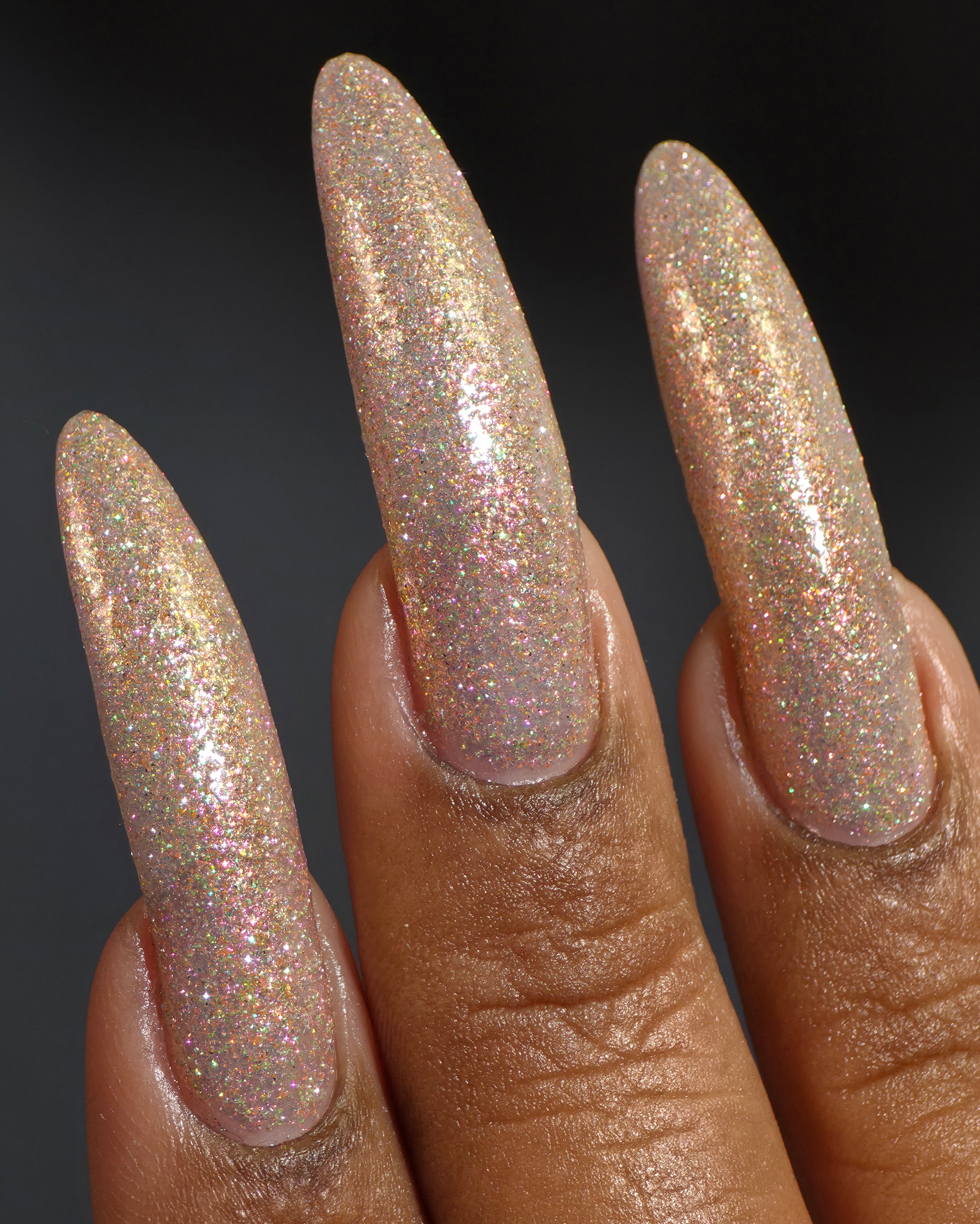 Resistance by Glitch Lacquer, sheer peach-gold reflective glitter swatch on deep skin, stiletto nails