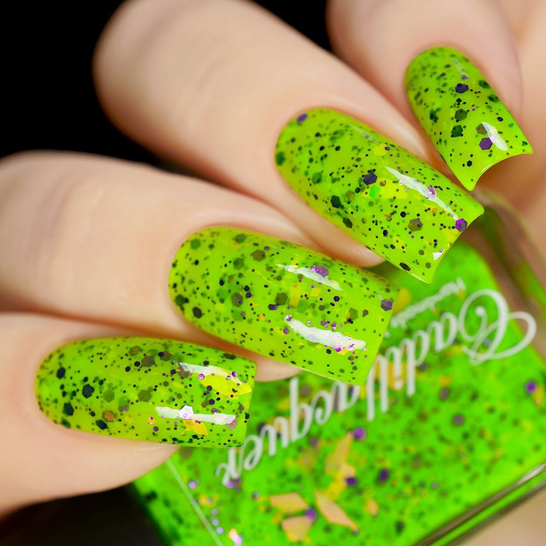 Dapper but no Dan by Cadillacquer, neon lime green with multi-size purple hex glitter and gold-yellow iridescent flakes, on a light skin tone hand
