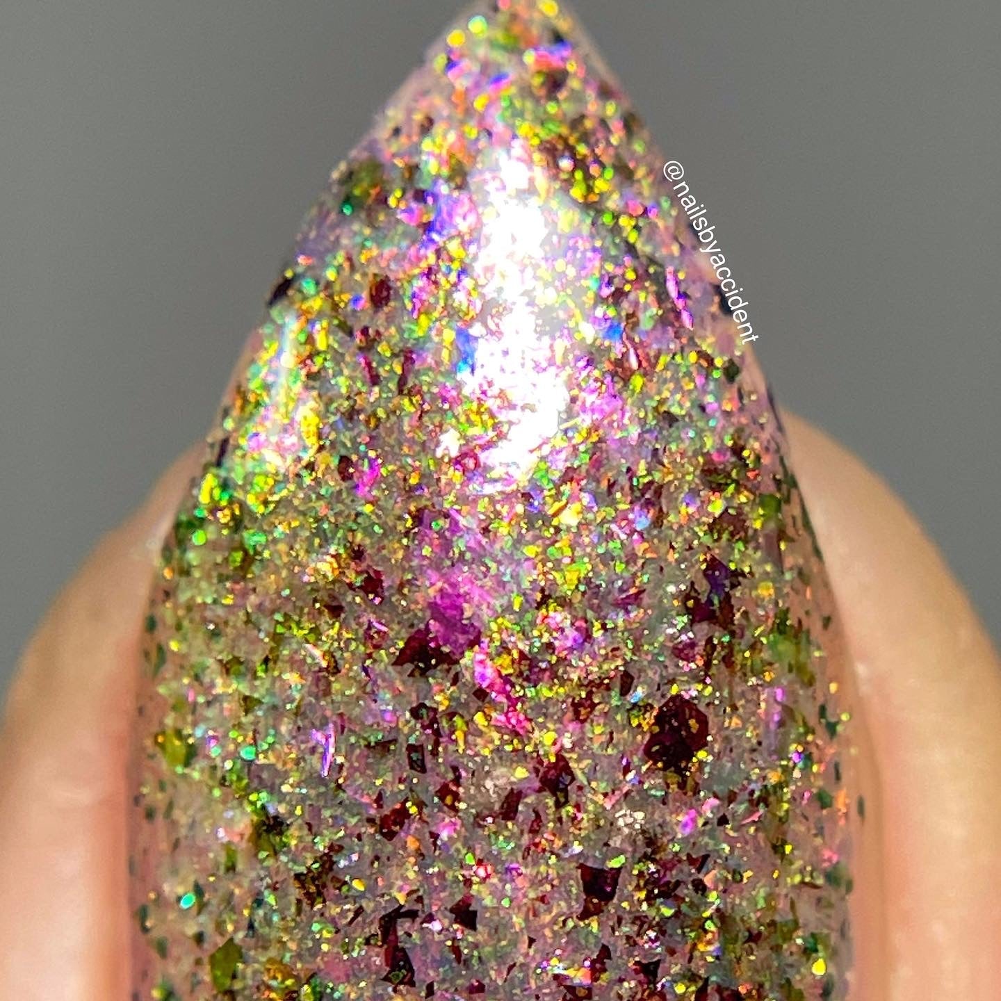Ayla the Scoliosis Dolphin by Dam Nail Polish, macro close-up of gold, magenta-red, and blue-to-green shifting multichrome flakies over a sheer dusty mauve base