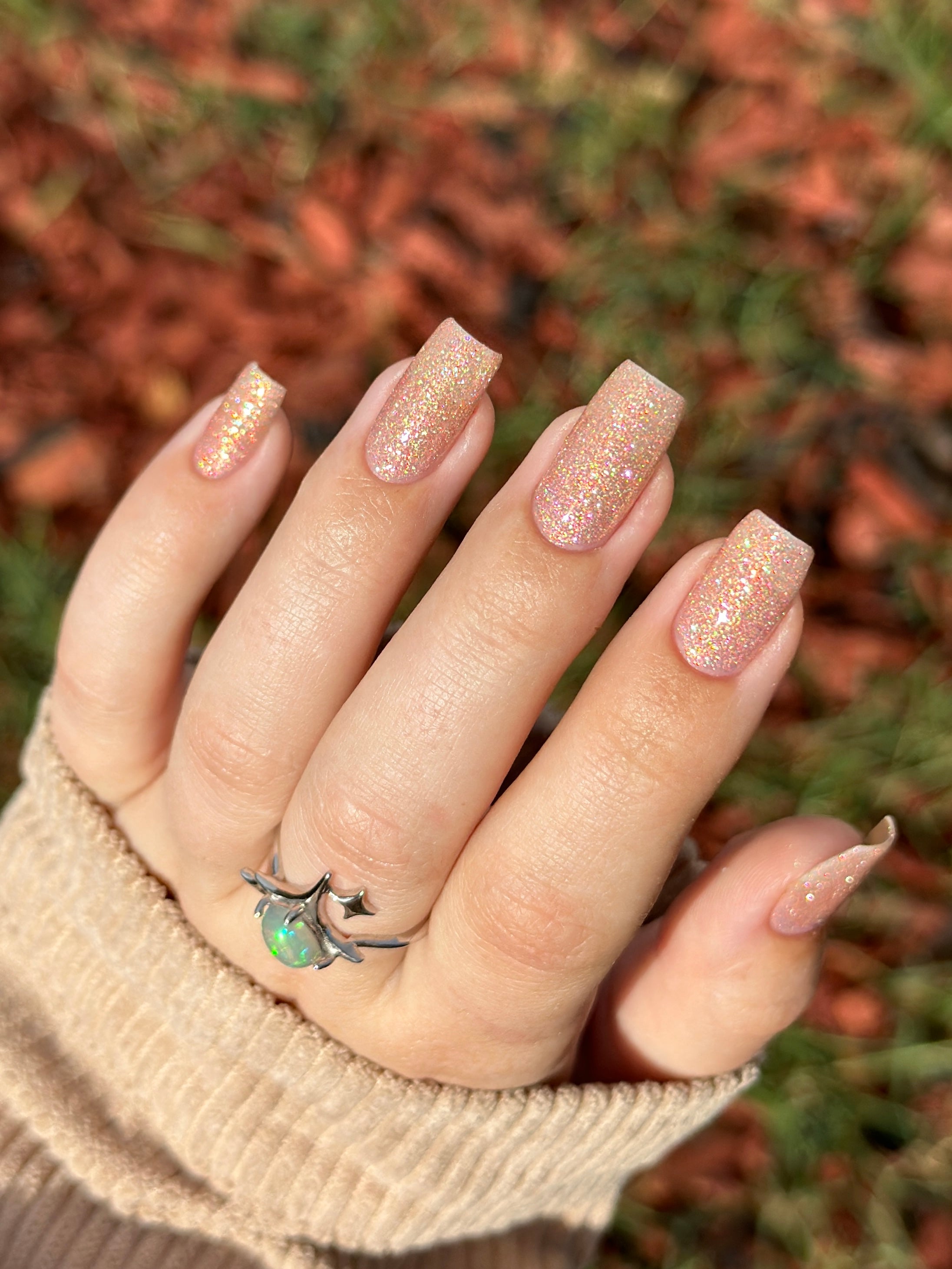 Resistance by Glitch Lacquer, sheer peach-gold reflective glitter swatch on light skin, squoval nails