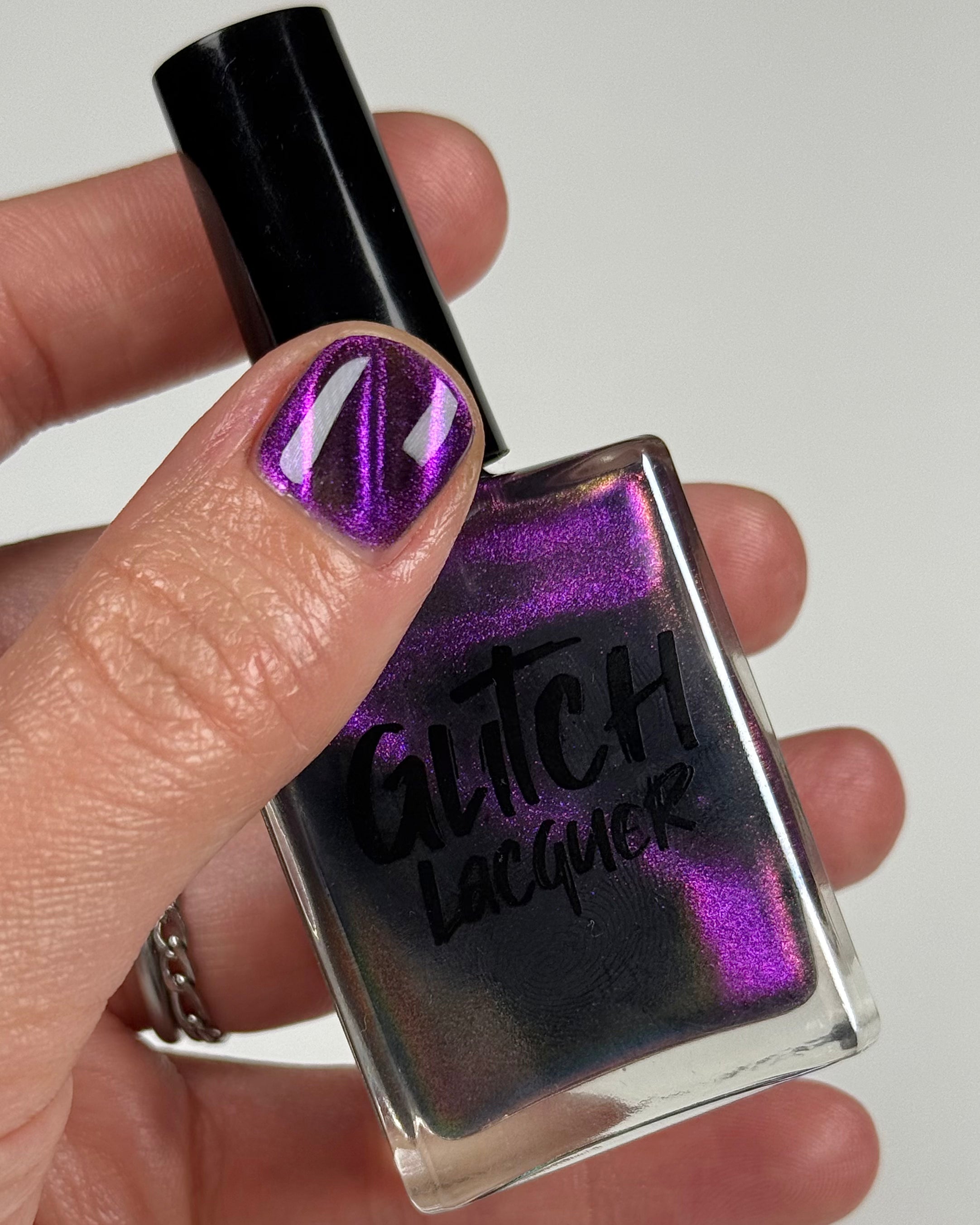 Habibi by Glitch Lacquer, dark purple-pink-gold magnetic bottle in hand, light-medium skin tone
