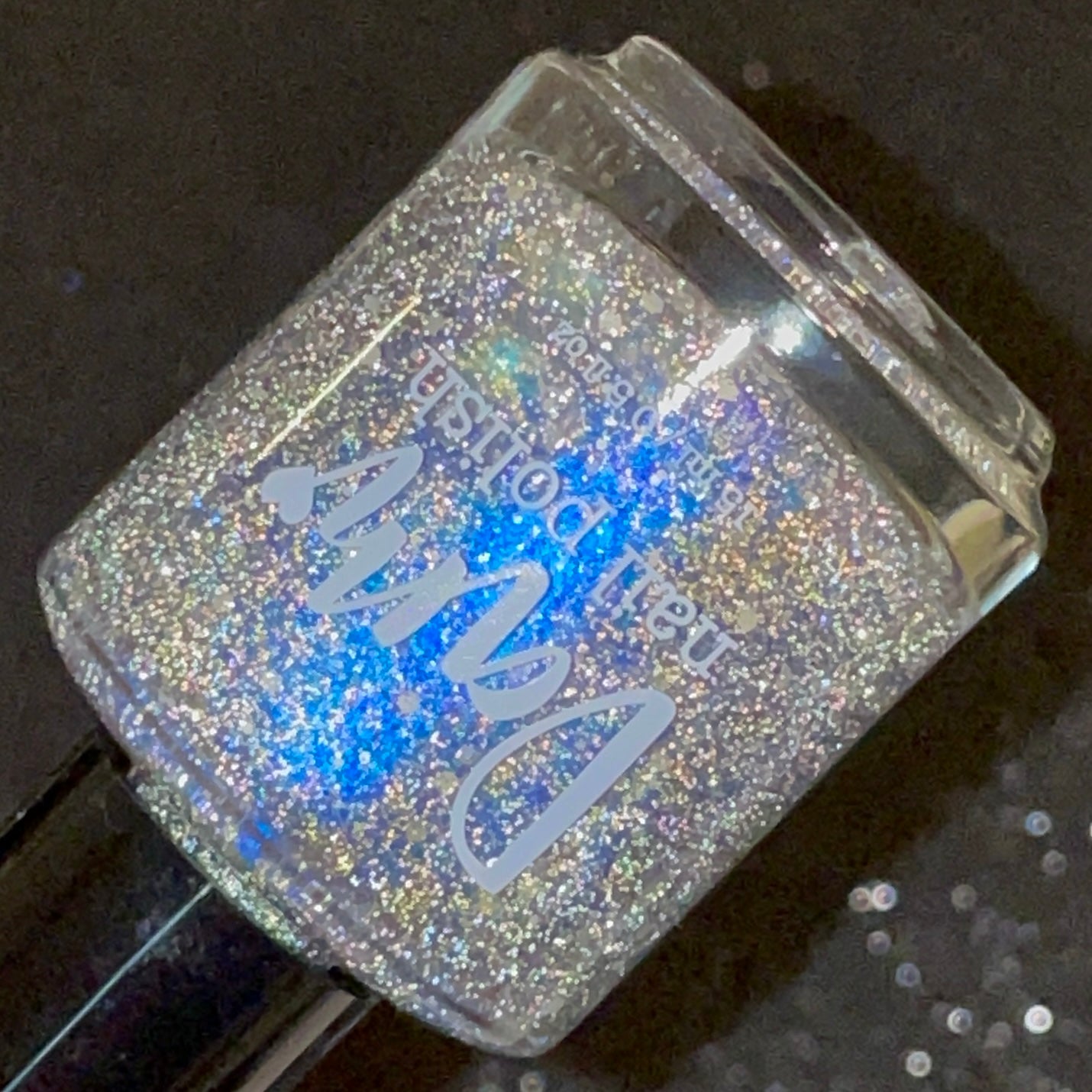 We're Off to See the Blizzard by Dam Nail Polish, black jelly base blazing with silver reflective microglitter and scattered white snow glitters under flash, bottle standalone product shot