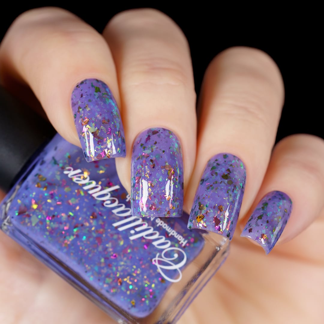 Cadillacquer Don't Worry purple pink chameleon iridescent crelly nail polish, bottle held with four-nail swatch, light skin, studio lighting