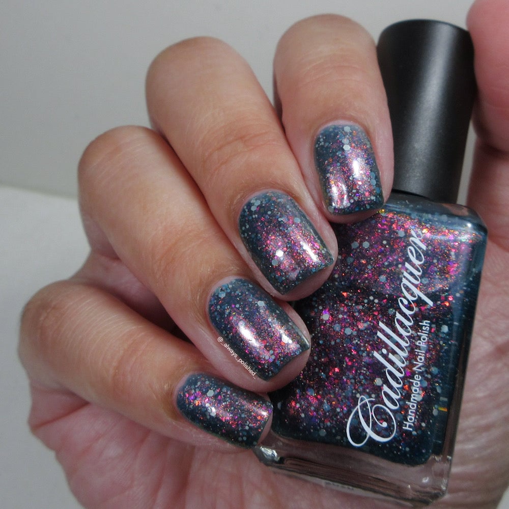 Cadillacquer I Don't Belong To You nail polish held with bottle, dark blue with flakies