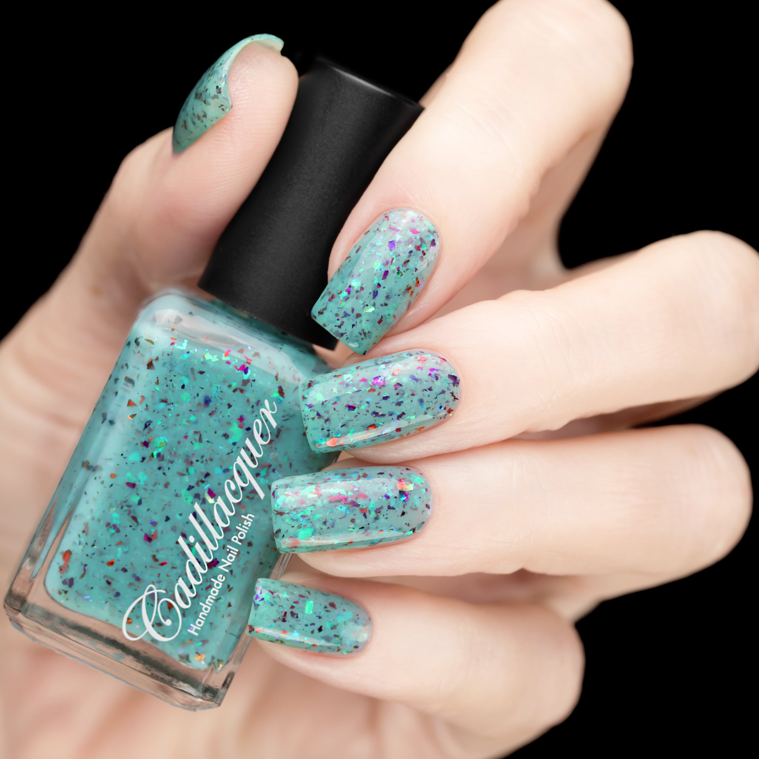 Cadillacquer Pastel Thoughts pastel teal purple chameleon iridescent crelly nail polish, bottle held with five-nail swatch, light skin, studio lighting