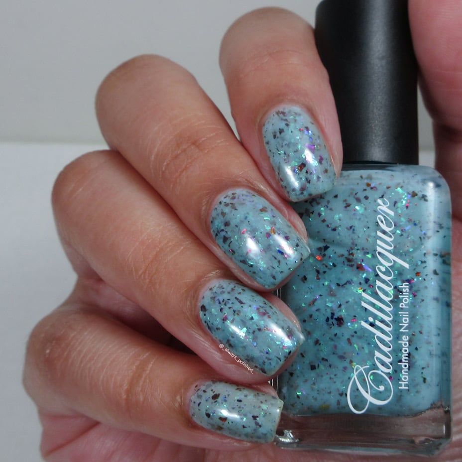Cadillacquer Pastel Thoughts pastel teal purple chameleon iridescent crelly nail polish, bottle held with four-nail swatch, light skin, bright daylight lighting