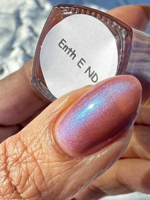 Enth E ND by Danglefoot Nail Polish, blue-brown shimmer bottle held in a light-medium hand