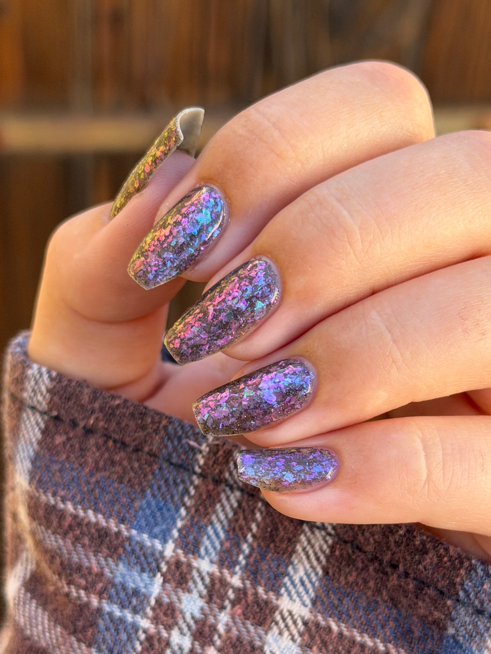 AVEN by Glitch Lacquer, soft black base, iridescent purple flakes, holo micro-glitter, on light skin tone coffin nails