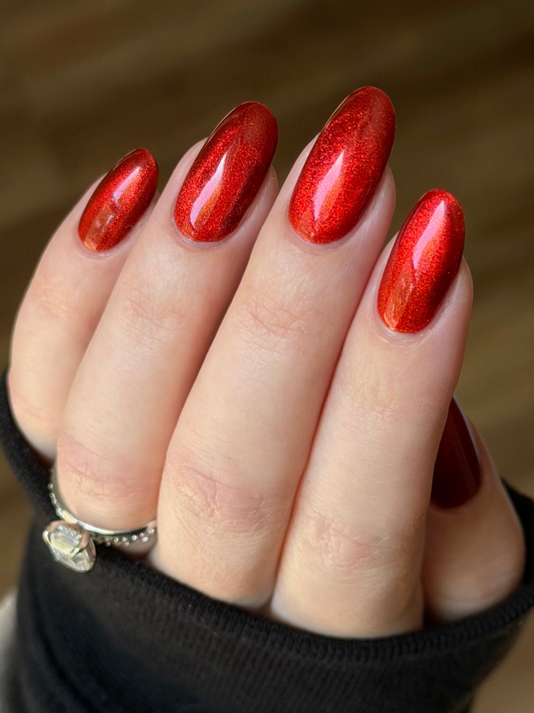 Stonewall by Glitch Lacquer, brick red jelly with red magnetic cat-eye shimmer, on light skin tone almond nails