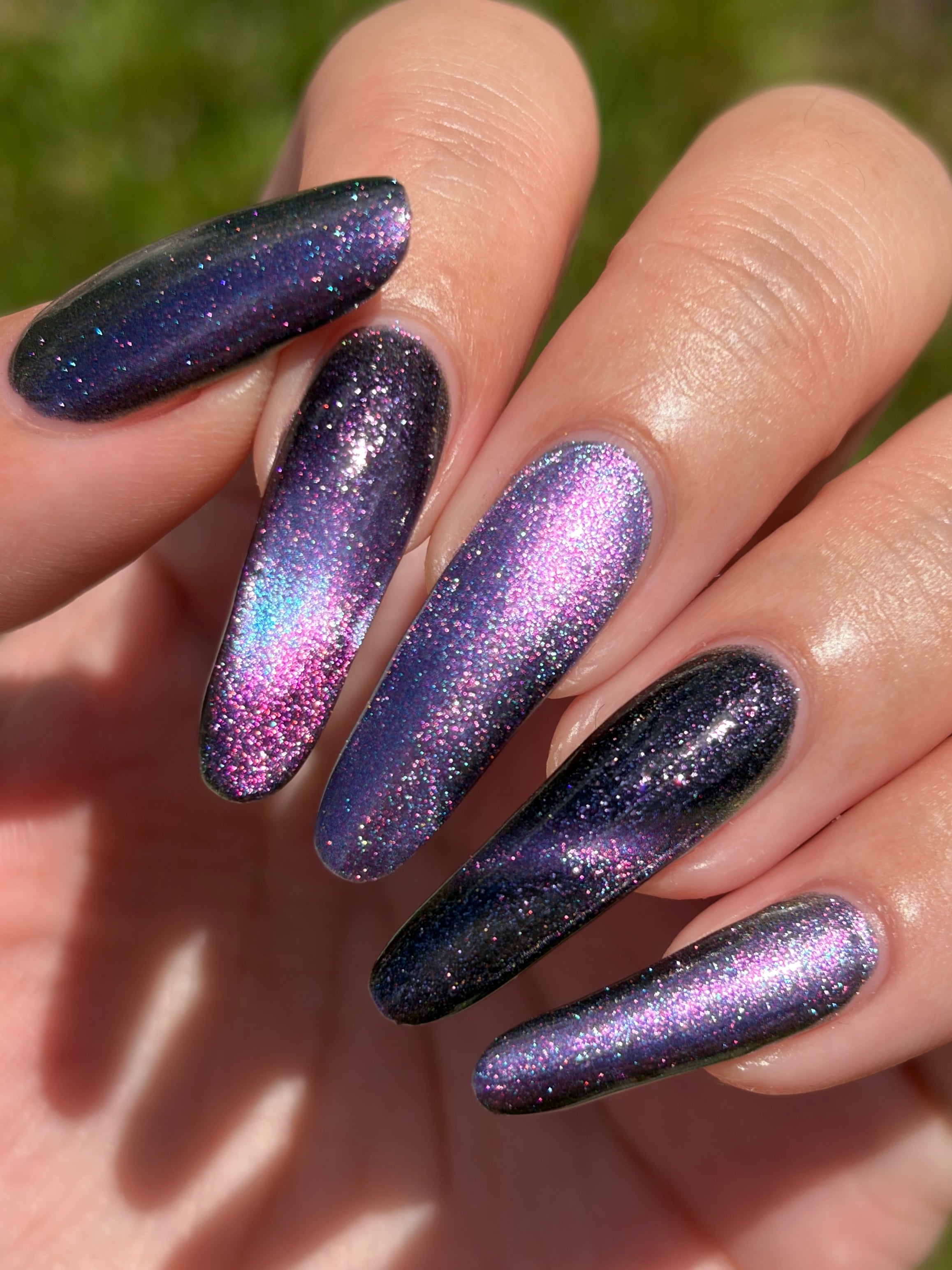 Lavender Menace by Glitch Lacquer, black jelly, purple sparkle, purple-to-blue magnetic, on light-medium skin tone almond nails