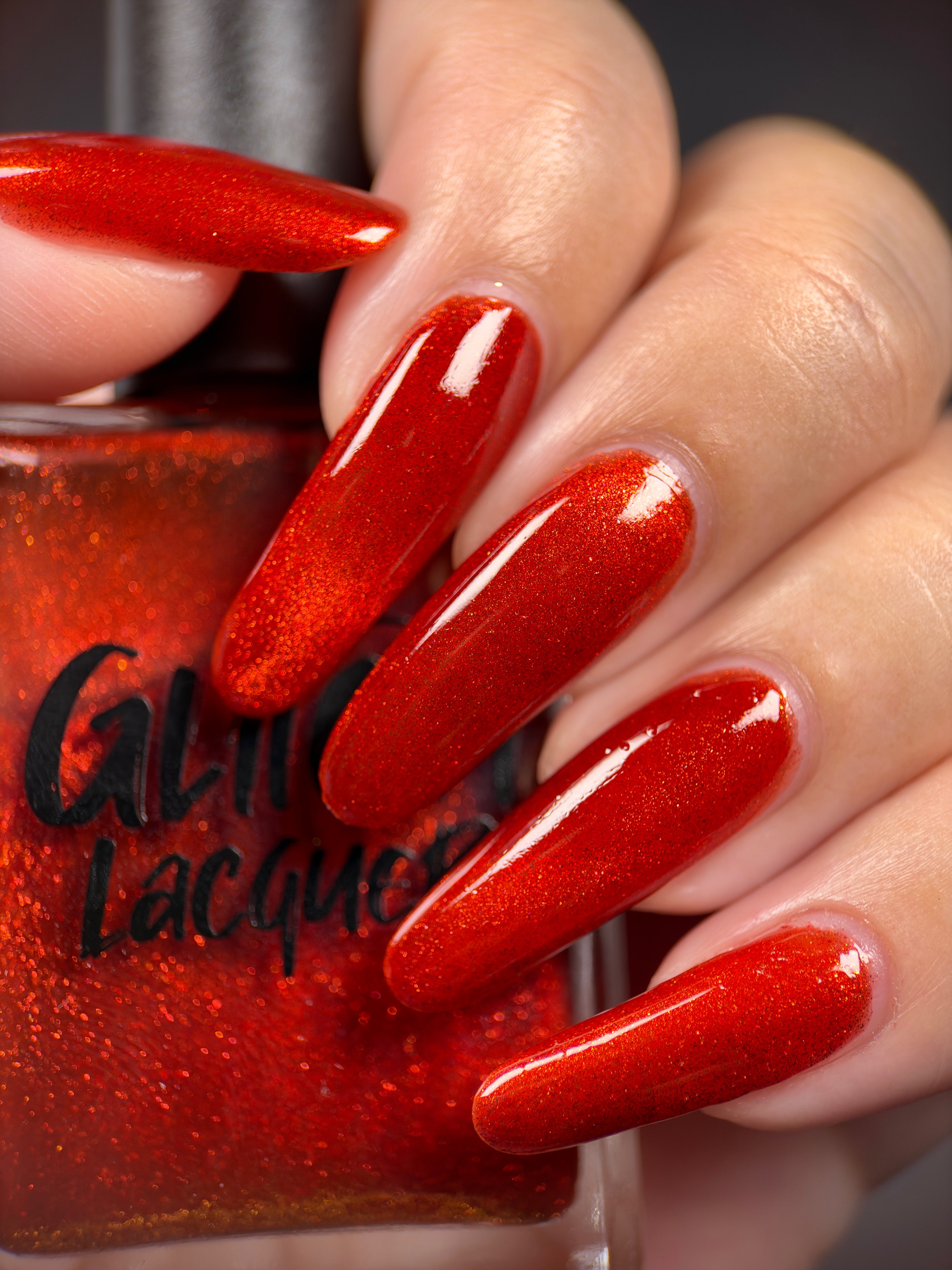 Stonewall by Glitch Lacquer, brick red magnetic jelly, bottle held in hand on light skin tone