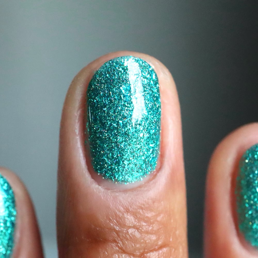 Mutant and Proud by Danglefoot Nail Polish, green-teal holographic reflective glitter flakie on a light-medium skin tone hand