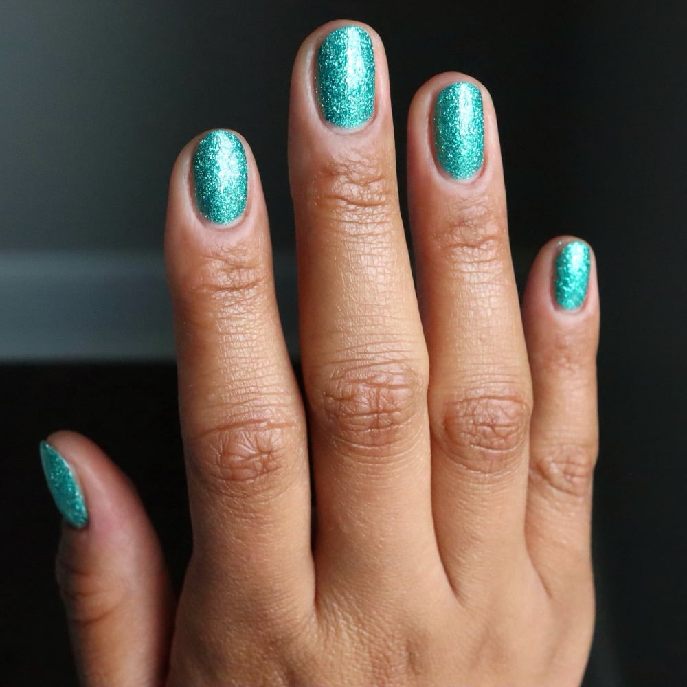 Mutant and Proud by Danglefoot Nail Polish, green-teal holographic reflective glitter flakie on a medium skin tone hand