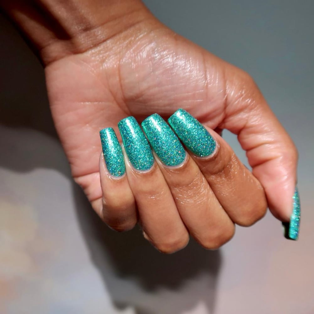Mutant and Proud by Danglefoot Nail Polish, green-teal holographic reflective glitter flakie on a medium-deep skin tone hand