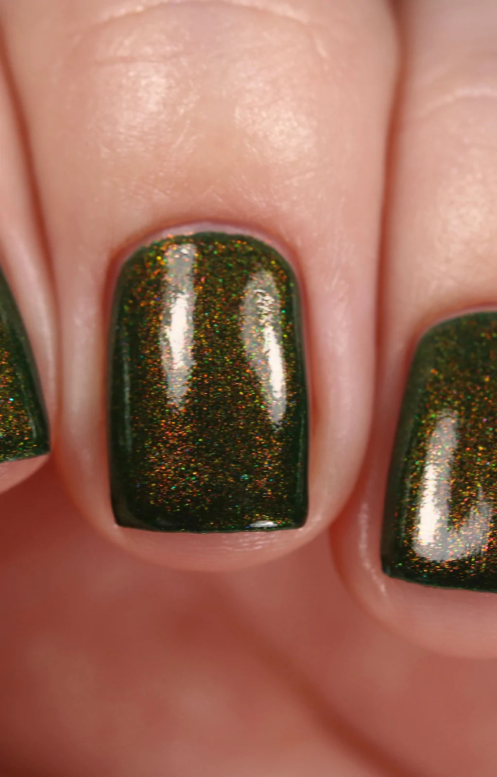 Artemis by Starrily, forest green shimmer with fine copper-to-gold-green multichrome particles under direct flash, on a light skin tone hand