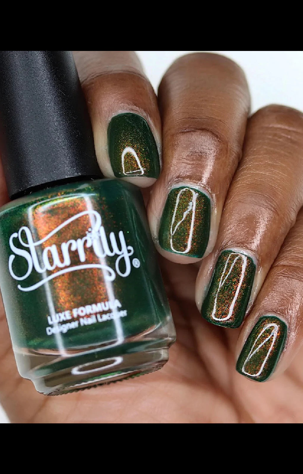 Artemis by Starrily, forest green copper-to-green duochrome shimmer under studio light, bottle held in a deep hand