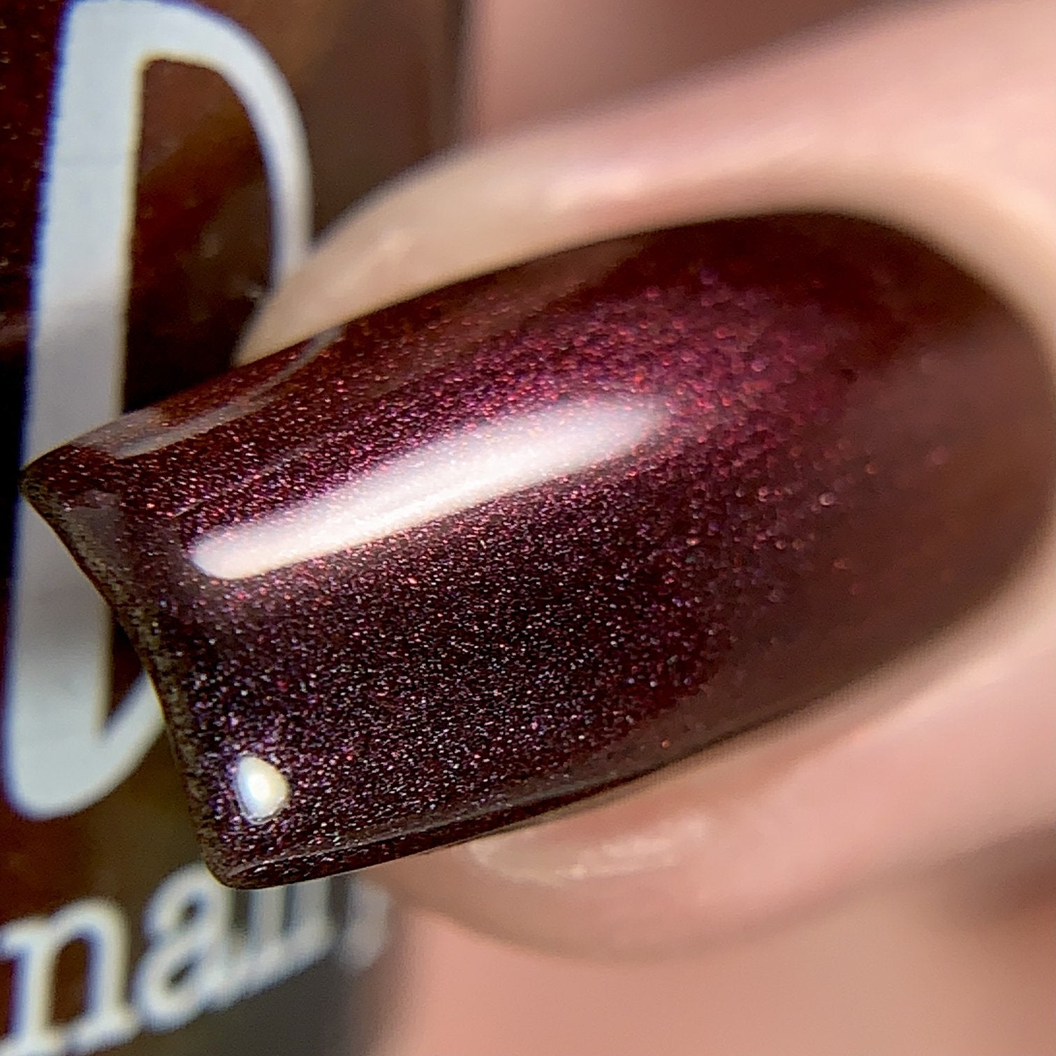Change of Heart by Dam Nail Polish, black-red multichrome with vivid red-to-orange microflake shift under direct flash, on a light skin tone hand
