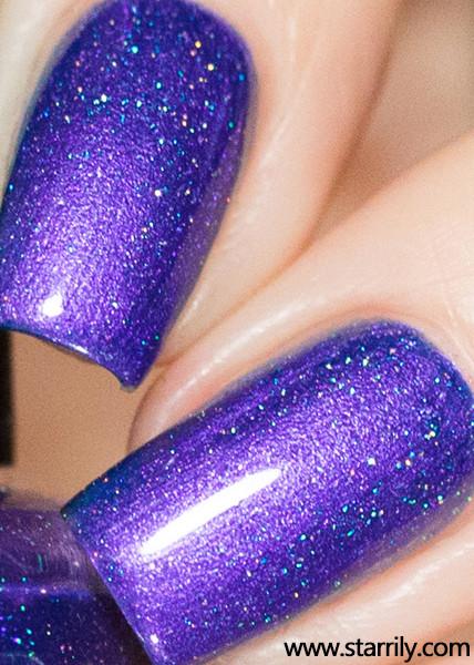 Violet Twilight by Starrily, medium blue-violet holographic shimmer with dense teal-blue linear holo scatter under direct flash, on a light skin tone hand