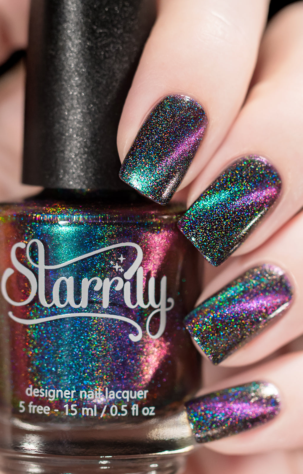 Dark Energy by Starrily, holographic multichrome magnetic showing green-to-purple-to-teal shift with dense holographic sparkle, bottle held in a light hand