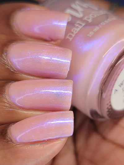 A Whimsical Dream by Dam Nail Polish, sheer pink jelly base with blurple-to-cool-blue iridescent shimmer shift, on a medium-deep skin tone hand
