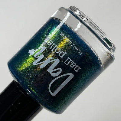 Moody Modern by Dam Nail Polish, deep navy base with gold-to-green shifting shimmer, angled view revealing shimmer depth, bottle standalone product shot