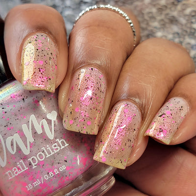 Shimmer Storm by Dam Nail Polish, warm champagne base with gold shimmer and scattered hot pink glitter, on a medium skin tone hand