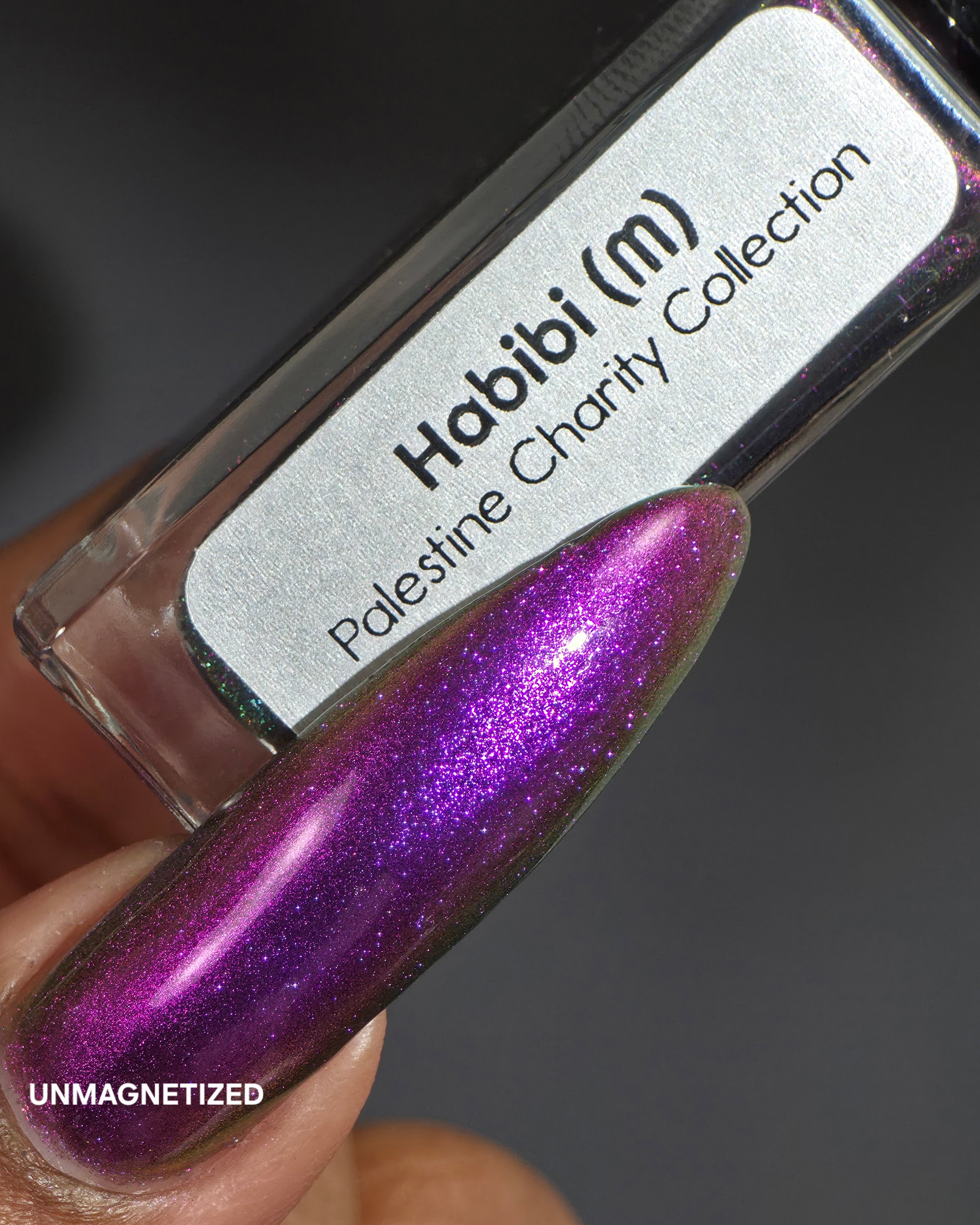 Habibi by Glitch Lacquer, dark magnetic swatch and bottle label on medium-deep skin tone