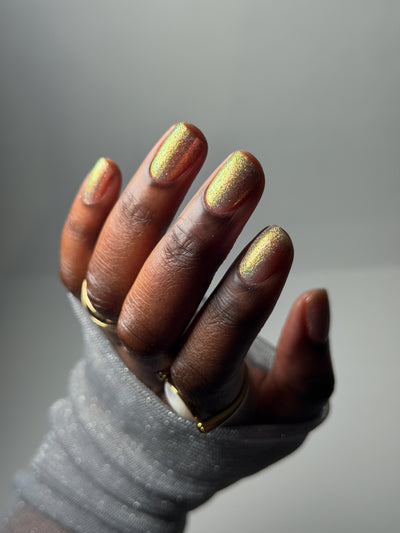 Lavender Haze by Glitch Lacquer on five round nails, very light purple polish with pink-yellow-green-teal multichrome reflect catching strong shifts, deep skin tone, studio lighting.