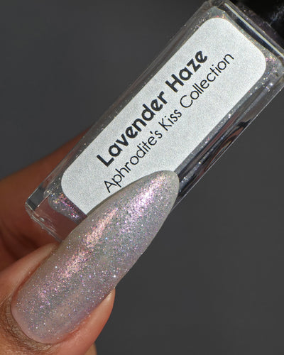 Lavender Haze by Glitch Lacquer on four long almond nails alongside the bottle, very light purple polish with pink-yellow-green-teal multichrome reflect and red reflective glitters, light skin tone, bright studio lighting.