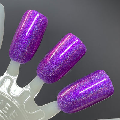 Sleigh My Name, Sleigh My Name by Dam Nail Polish, vivid purple base with purple-to-pink shifting shimmer and linear holographic rainbow scatter, swatch stick
