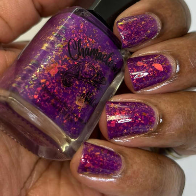 Evening in Provence by Chamaeleon Nails, magenta jelly with orange-red, gold, and copper UCC flakies blazing under direct flash, bottle held in a deep hand
