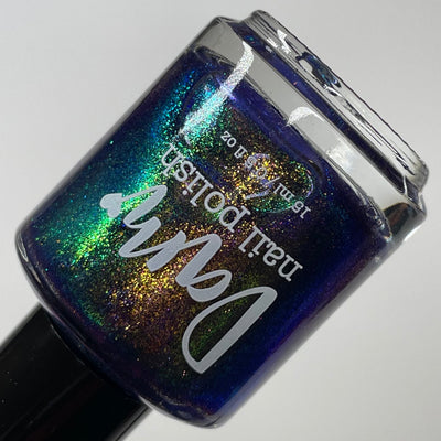 Sandman by Dam Nail Polish, deep blurple jelly with vivid gold, green, and blue fine metallic shimmer under direct flash, bottle standalone product shot