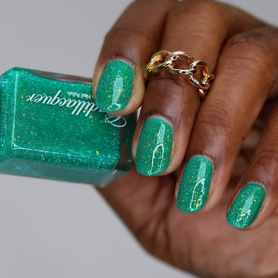 Blausee by Cadillacquer, teal green crelly with light blue-green reflective glitter and scattered yellow-green iridescent flakies, bottle held in a rich hand