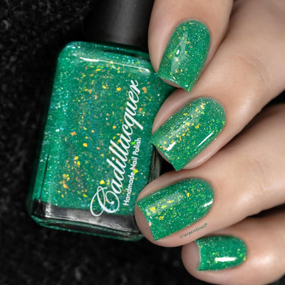 Blausee by Cadillacquer, vivid emerald-teal crelly with holographic micro-glitter and yellow-green iridescent flakes, bottle held in a light-medium hand