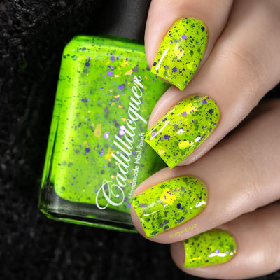 Dapper but no Dan by Cadillacquer, neon lime green glitter flakie showing purple hex glitter and yellow-orange iridescent flake scatter, on a light-medium skin tone hand