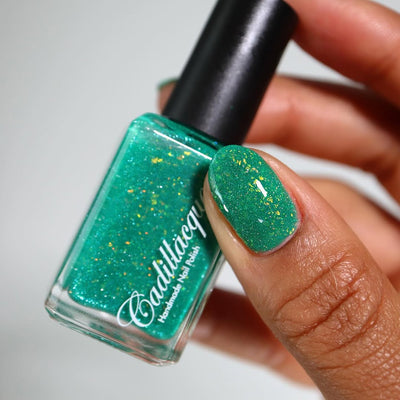 Blausee by Cadillacquer, teal green crelly with yellow-green iridescent flakies and light blue-green reflective glitter, bottle held in a medium-deep hand