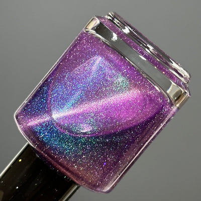 Moonlight Mist by Dam Nail Polish, medium-dark purple holographic shimmer magnetic showing vivid blue-green flash and pink magnetic sweep, bottle standalone product shot