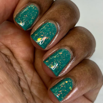 Kuang Si Falls by Chamaeleon Nails, neon teal flakie jelly with dense orange and yellow iridescent flakes across two hands, on a deep skin tone hand