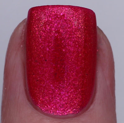 Beach Towel by 'Ard As Nails, deep raspberry red with iridescent magenta-to-red multichrome flakes under direct flash, on a light skin tone hand