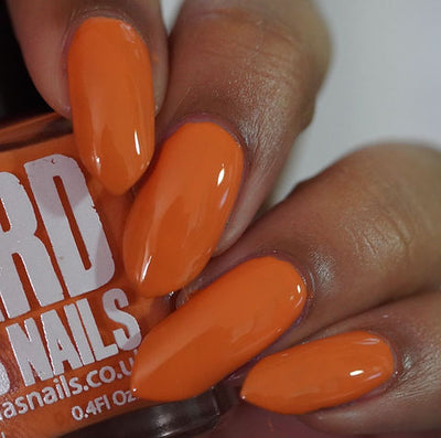 Sunset by 'Ard As Nails, vivid warm orange creme with smooth glossy finish, on a medium-deep skin tone hand