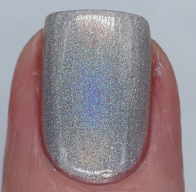 Cosmic by 'Ard As Nails, silver linear holographic with dense blue and violet holo scatter under direct flash, on a light skin tone hand