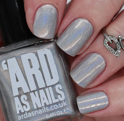 Cosmic by 'Ard As Nails, silver-grey linear holographic with strong blue and violet holo streaks, bottle held in a light hand