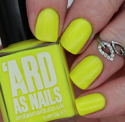 Lightning Speed by 'Ard As Nails, vivid chartreuse-yellow neon creme under indoor warm lighting, bottle held in a light skin tone hand