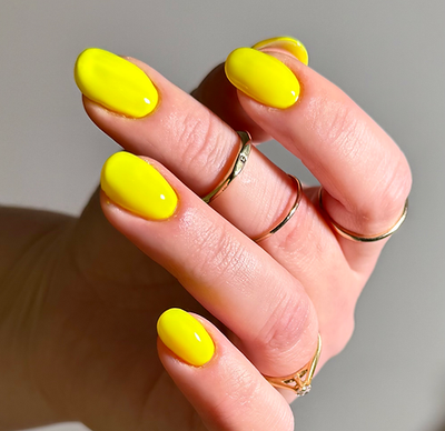 Lightning Speed by 'Ard As Nails, electric neon yellow creme with high-gloss finish under studio lighting, on a light skin tone hand