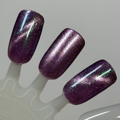Moonlight Mist by Dam Nail Polish, dark purple multichrome magnetic with pink highlight band, green-blue shimmer, and fine holographic sparkle, swatch stick