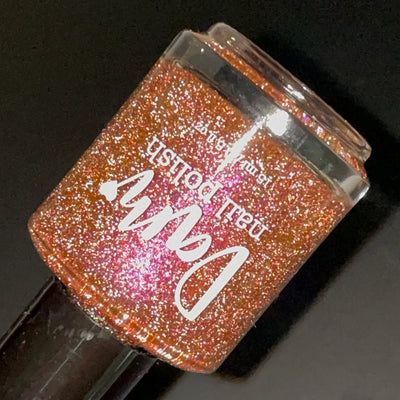 I Like Cheese but I'm Lactose by Dam Nail Polish, muted orange base with pink-to-orange duochrome shimmer and silver reflective glitter lit under direct flash, bottle standalone product shot