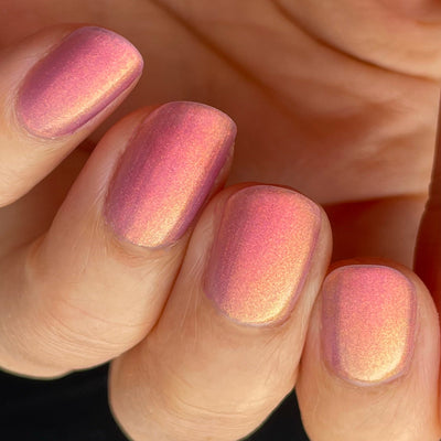 Maui by Dam Nail Polish, multichrome shimmer mid-shift from pink-rose to warm golden-orange with deep mauve edges, on a light skin tone hand