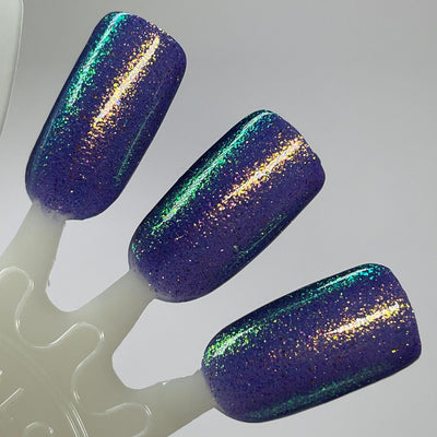 Sandman by Dam Nail Polish, deep blurple jelly with diagonally streaking gold, teal-green, and blue ultrachrome shimmer particles, swatch stick