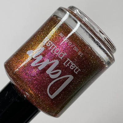 I Like Cheese but I'm Lactose by Dam Nail Polish, muted burnt orange base showing pink-to-orange multichrome shimmer with silver reflective microglitter, bottle standalone product shot