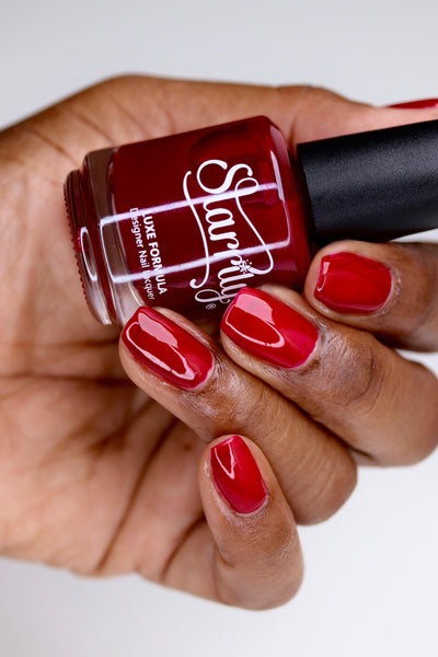 Bloodbelly Jelly by Starrily, medium red glossy jelly with buildable coverage, bottle held in a medium-deep hand